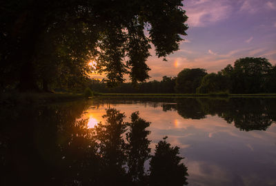 Silhouette trees by lake against sky during sunset