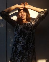 Smiling young woman standing against the wall