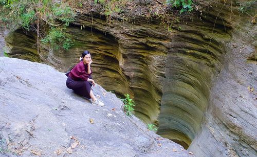 Asian woman sitting on rock formation at sila laeng, thailand's canyon.