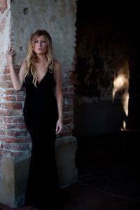 Portrait of young beautiful woman standing by wall