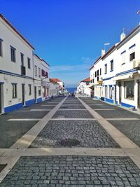 Surface level of street amidst buildings against blue sky
