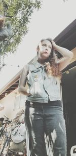 Low angle portrait of woman standing against cars