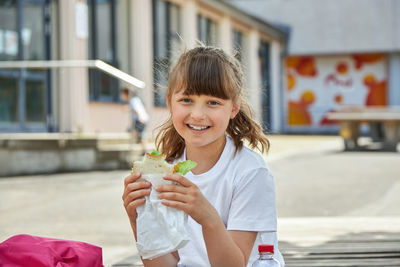 Lunch at school. a charming girl is eating breakfast, a snack at recess in the schoolyard. 