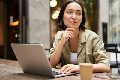 Businesswoman using laptop while sitting at table