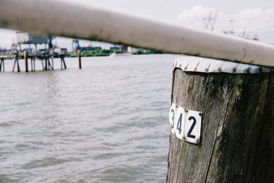 Close-up of number on wooden post in sea