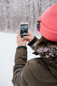 Man photographing with mobile phone in snow