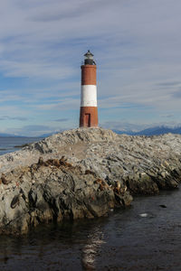 Lighthouse by sea against sky