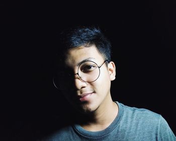 Close-up portrait of handsome young man against black background