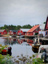 Sailboats moored on lake by buildings against sky