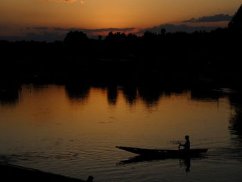 Silhouette man in lake during sunset