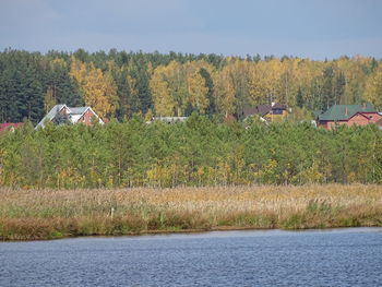 Scenic view of trees by houses against sky