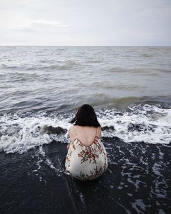 Rear view of woman looking at sea against sky