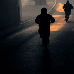 Rear view of silhouette man and woman walking on road