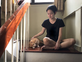 Full length of woman sitting dog at home