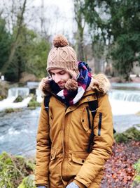 Smiling young man standing with river in background during winter