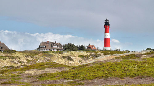 Lighthouse by building against sky