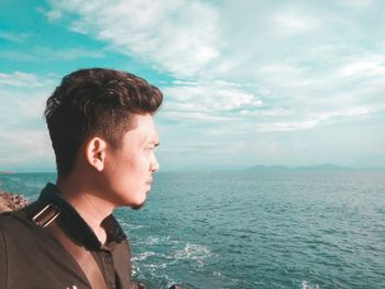 Young man looking at sea against sky