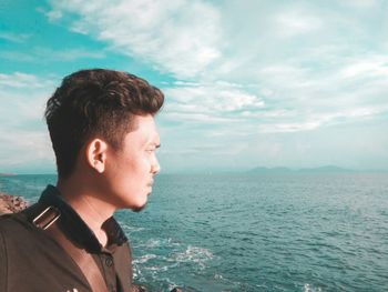 Portrait of young man looking away against sky