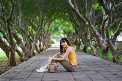 Portrait of young woman sitting on tree