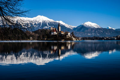 Scenic view of lake by snowcapped mountains against sky