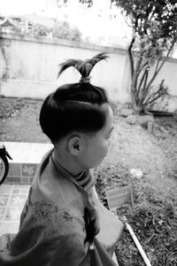 High angle view of boy getting hair cut while sitting outdoors