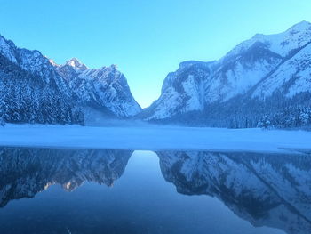 Scenic view of lake and snowcapped mountains against clear blue sky