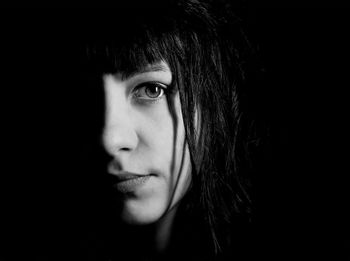 Close-up portrait of a beautiful young woman over black background