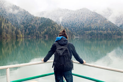 Man with the ponytail while wearing a backpack and jacket stands back and looks forward ritsa lake