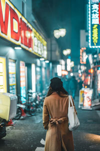 Rear view of woman standing on street at night