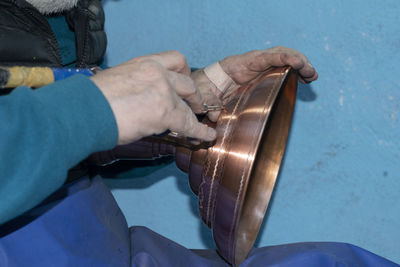 Close-up of man working against blue sky