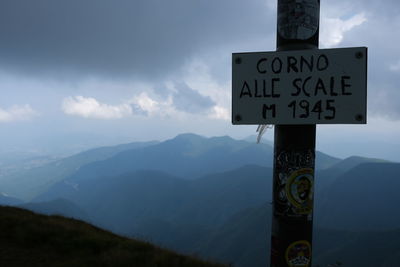 Information sign on mountain against sky