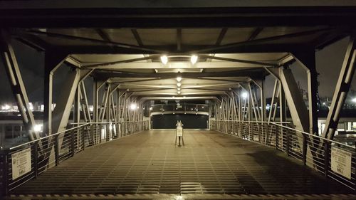 Rear view of woman walking on illuminated bridge