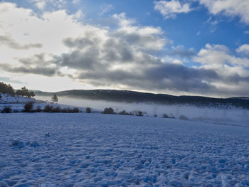 Scenic view of snow covered field against sky