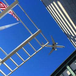 Low angle view of american flag waving against airplane flying in clear sky