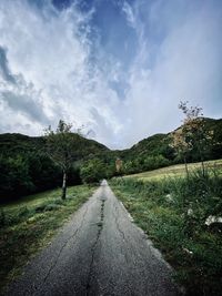 Road amidst trees against sky