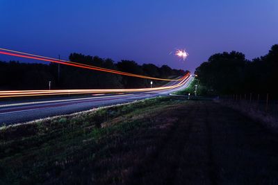 Light trails on road against sky at night