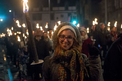 Portrait of woman standing against illuminated city at night