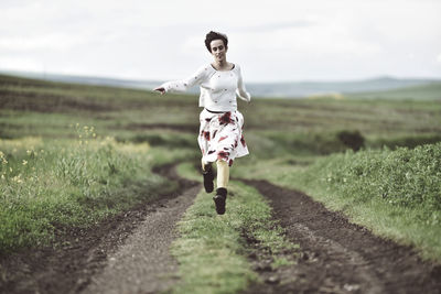 Full length of young woman running on field