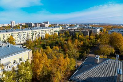 High angle view of trees and buildings against blue sky