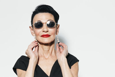 Portrait of young woman wearing sunglasses against white background