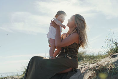 Woman with child arms  against sky