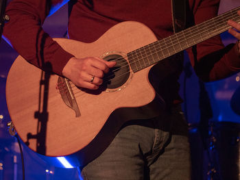 Midsection of musician playing guitar at music concert