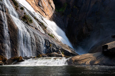 Ezaro waterfall water crashing on lake between rocks in spain