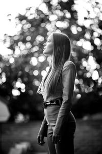 Side view of woman standing against tree