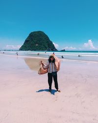 Full length of woman standing at beach against sky