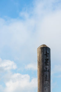 Low angle view of wooden post against sky