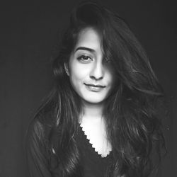 Portrait of smiling young woman against black background