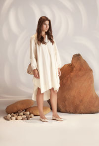 Portrait of young woman standing against wall