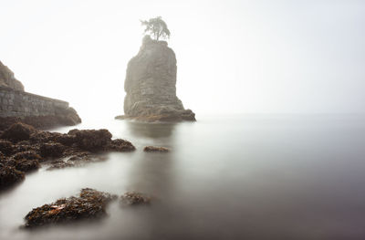Rock formation on beach against sky