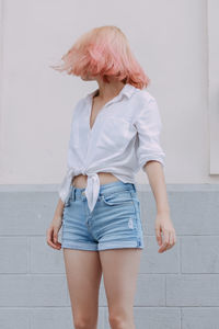 Woman with dyed hair standing against wall